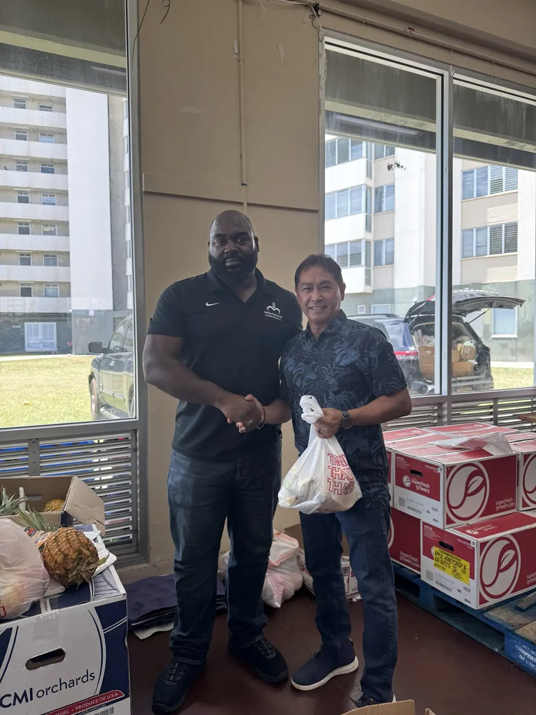 Coach Jeremy McLean thanking a community partner for supporting a food distribution project