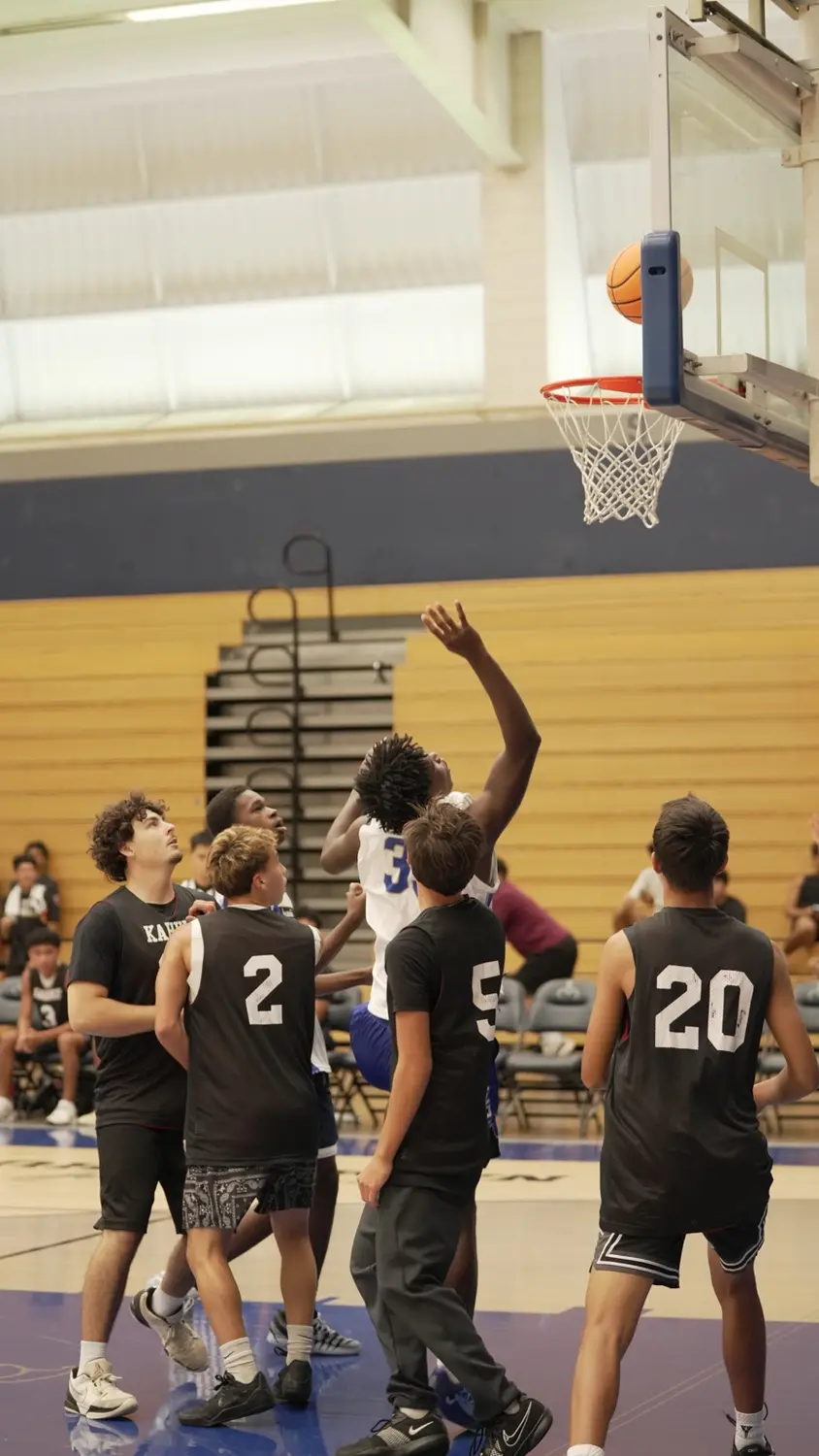 Varsity: Moanalua Fall League player shooting over defenders near the basket