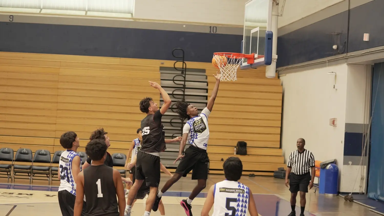 Varsity: Moanalua Fall League player finishing at the basket over a defender